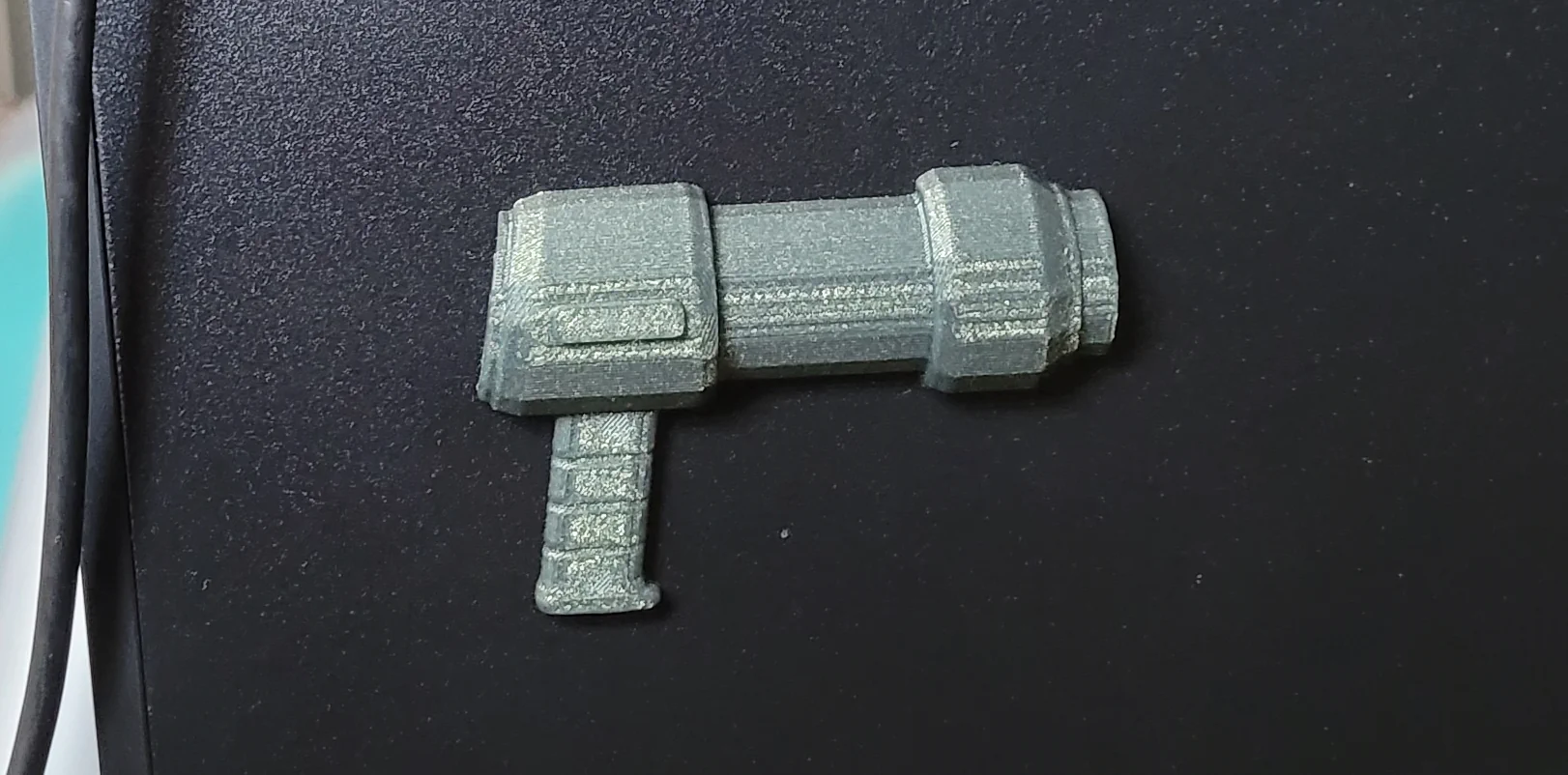 A 3D-printed half of an N5 Blaster that's hanging on the side wall of a PC
